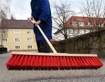 Hausmeister Walter Müller beseitigt am Dienstag (11.03.2003) im niederbayerischen Deggendorf mit einem Besen den Splitt von einer Hofeinfahrt. Nachdem der Schnee vielerorts verschwunden ist, laden die angenehmen Temperaturen zum Frühjahrsputz ein. Fotograf: Armin Weigel dpa/lby