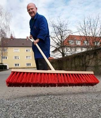 Hausmeister Walter Müller beseitigt am Dienstag (11.03.2003) im niederbayerischen Deggendorf mit einem Besen den Splitt von einer Hofeinfahrt. Nachdem der Schnee vielerorts verschwunden ist, laden die angenehmen Temperaturen zum Frühjahrsputz ein. Fotograf: Armin Weigel dpa/lby